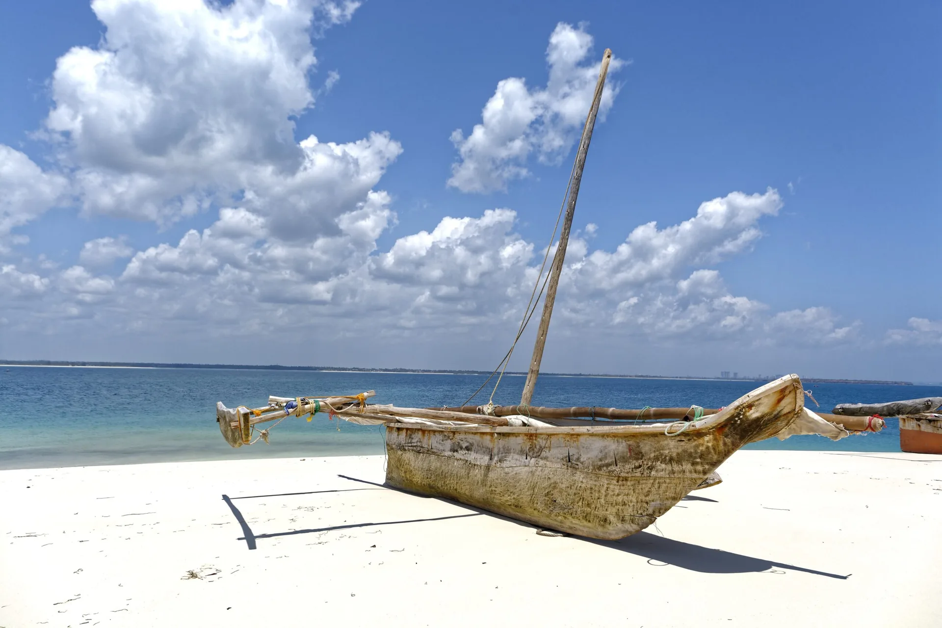 Traditional dhow resting on the shore beside turquoise sea in Zanzibar