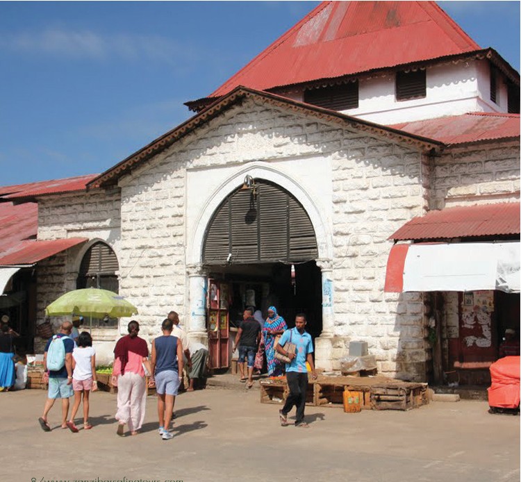 People walking towards a stone building entrance in Stone Town